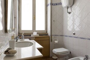 A bathroom with a sink, toilet, and bidet.