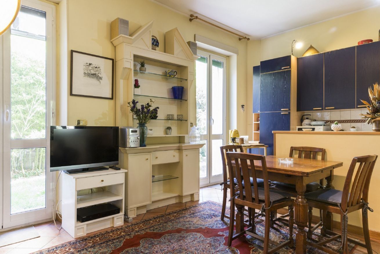 Une cuisine avec une table à manger, des chaises, un téléviseur et une fenêtre.