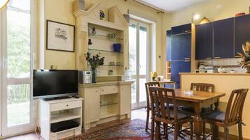 Une cuisine avec une table à manger, des chaises, un téléviseur et une fenêtre.