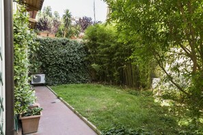 A garden pathway leading to a building with a large hedge and various plants. - Lemon Tree Apartment Vatican City (Roma)