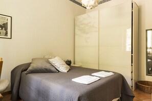 A neatly made bed with a grey bedspread and pillows, a framed picture on the wall, and a large mirror on the wall. - Lemon Tree Apartment Vatican City (Roma)