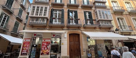 A building with a storefront labeled "Origenes Ibericos" featuring a variety of food items.