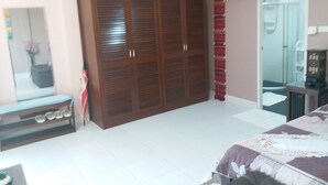 A bedroom with a large wardrobe, a bench with shoes, a bed, and a bathroom visible through an open door. - Résidence Chez Nous,, Deluxe Studios (50 M²) with hotel service + pool  (PHUKET)