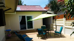 A patio with a table and chairs, a green umbrella, and a blue chair. - Résidence Chez Nous,, Deluxe Studios (50 M²) with hotel service + pool  (PHUKET)