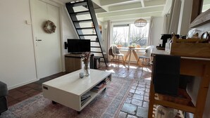 A cozy living room with a white coffee table, a TV, and a fireplace. - Sleeping in the countryside, near Amsterdam, The Hague and Utrecht (Bodegraven)