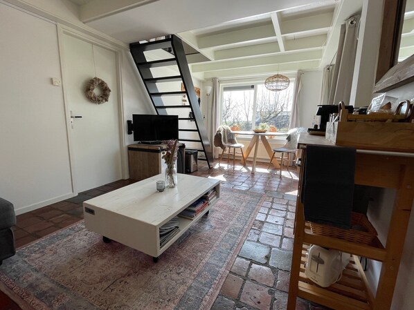 Una sala de estar acogedora con una mesa de centro blanca, un televisor y una chimenea.