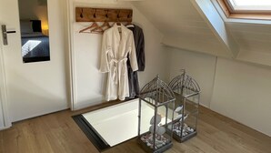 A room with a skylight, a wooden coat rack with clothes, a bathtub, and decorative birdcages with shells. - Sleeping in the countryside, near Amsterdam, The Hague and Utrecht (Bodegraven)