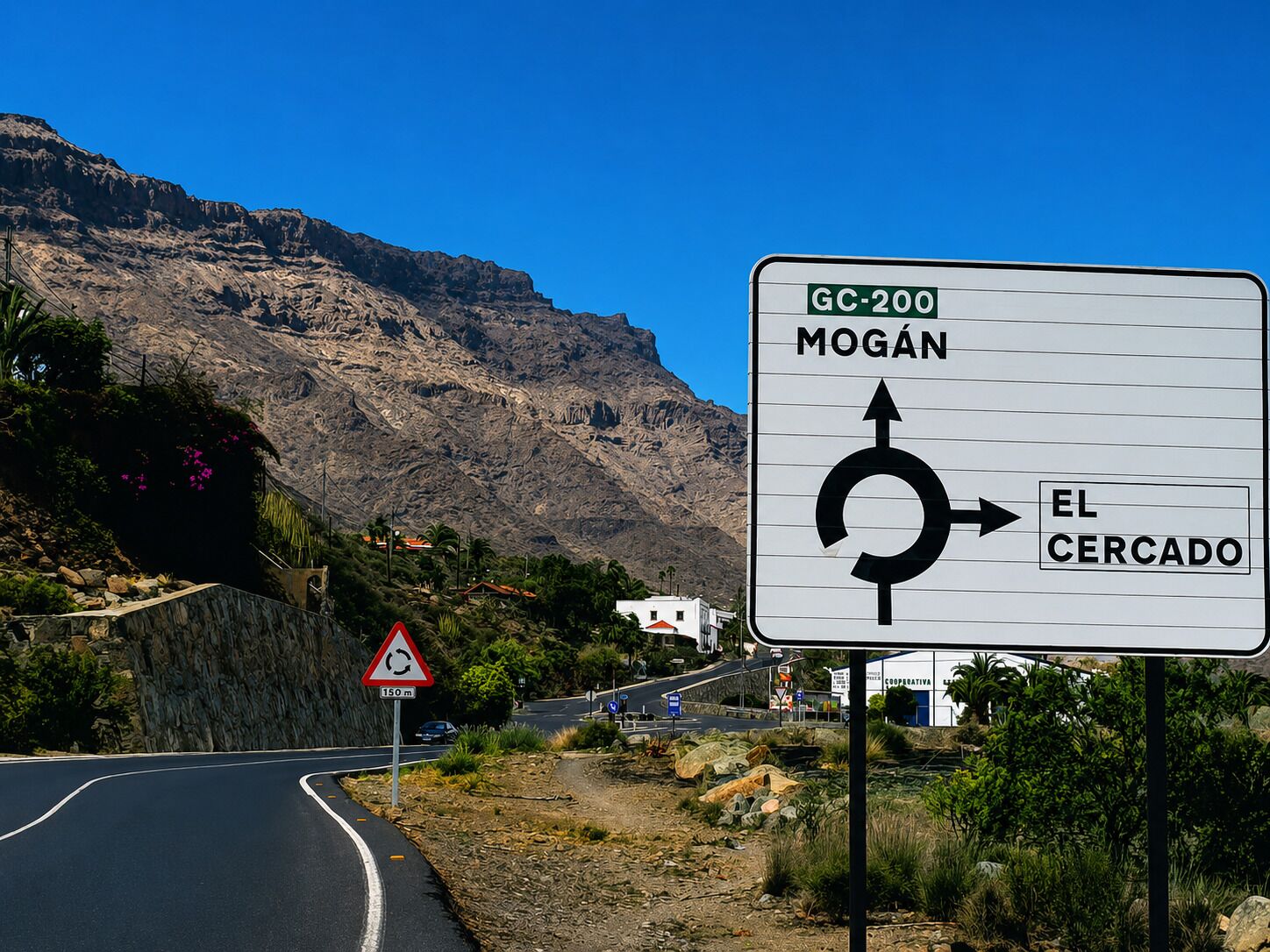 Señal de tráfico que indica una rotonda más adelante, con indicaciones hacia 'MOGAN' y 'EL CERCADO' por la GC-200.