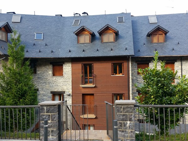 Un edificio de dos pisos con fachada de piedra, varias ventanas y un balcón de madera.