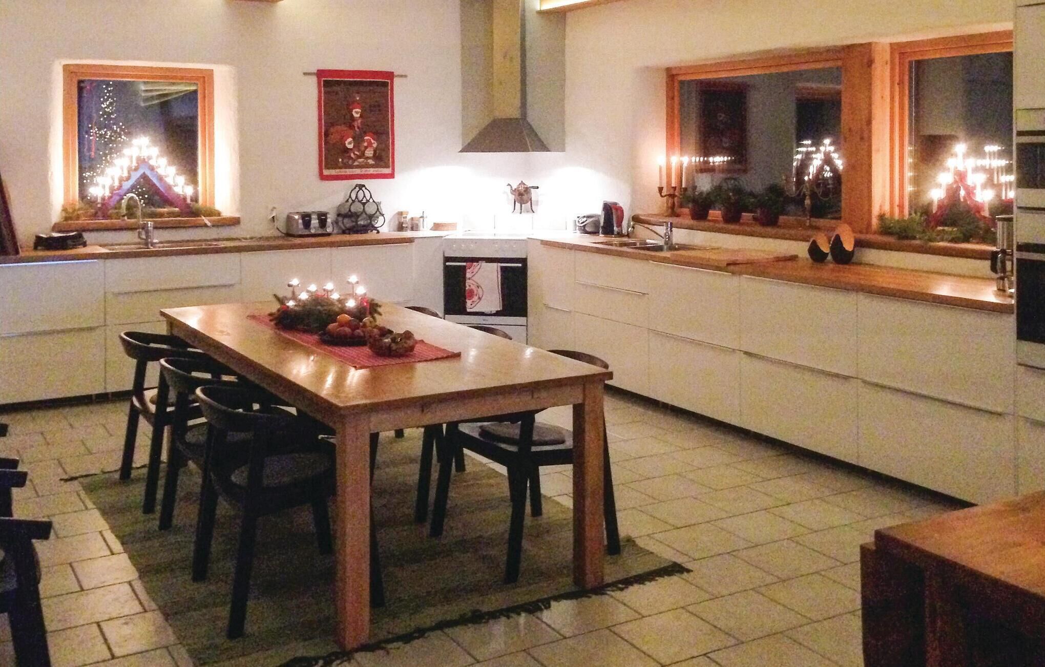A kitchen with a dining table set for four, a small oven, and a window with a view of fireworks.