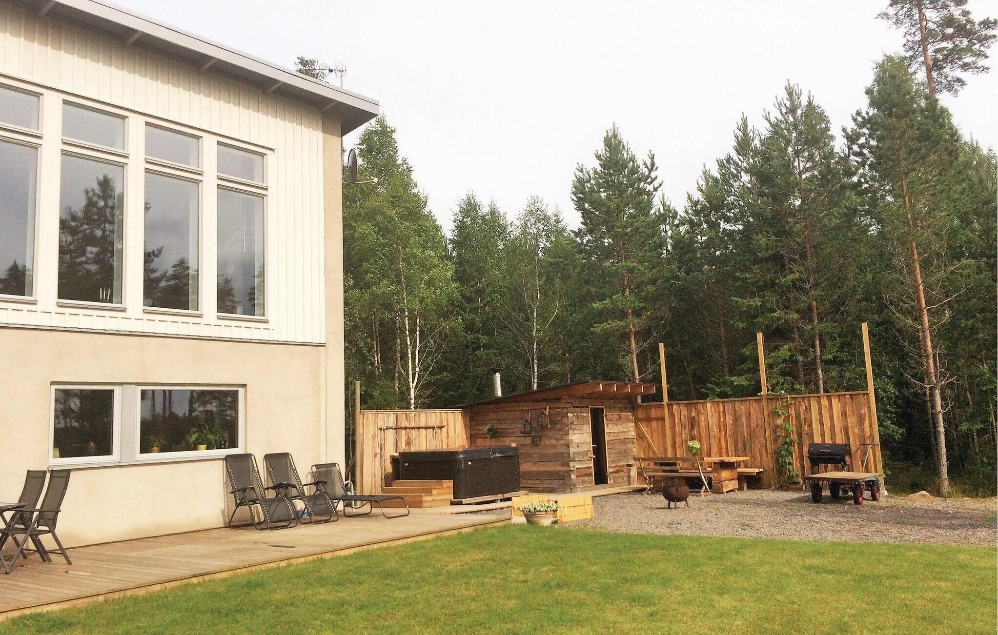 Moderni, kaksikerroksinen talo, jossa on patio, ulkotila oleskelua varten ja puinen mökkimainen rakennelma.