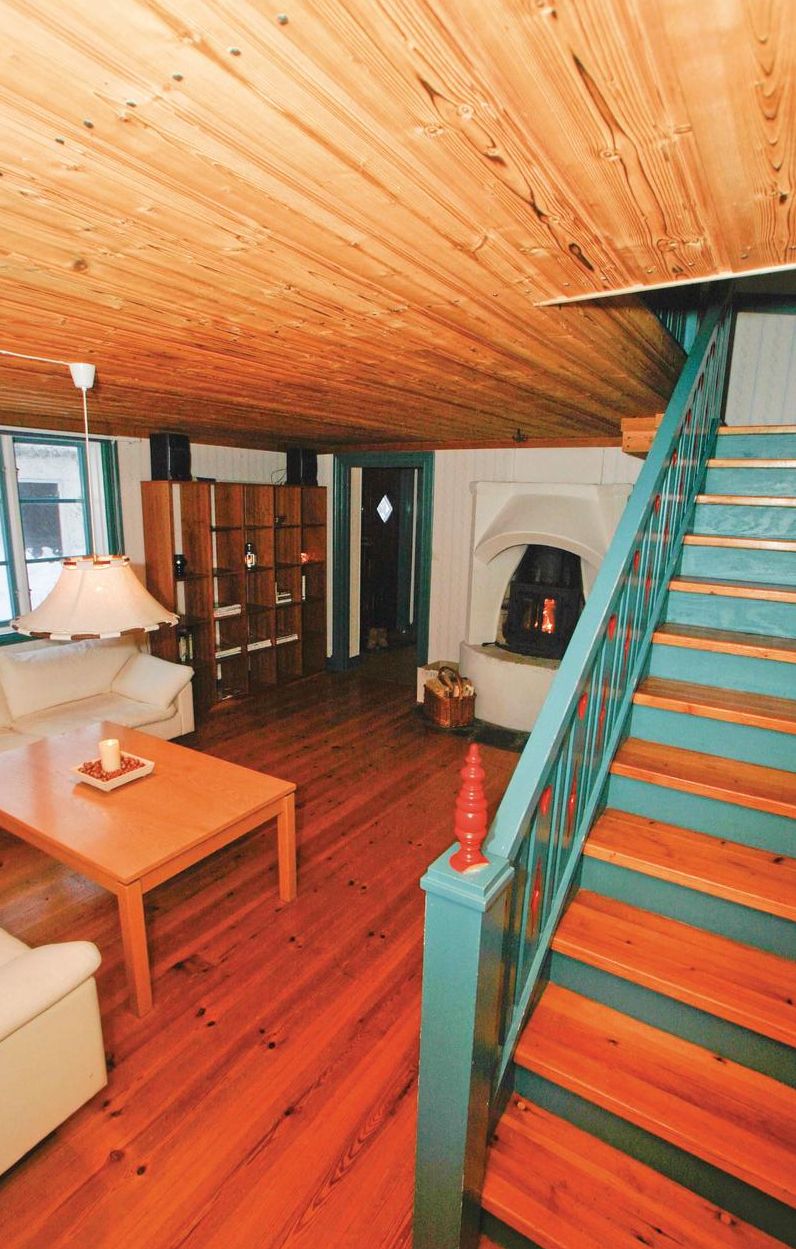 A wooden-floored living room with a staircase, a fireplace, and a bookshelf.