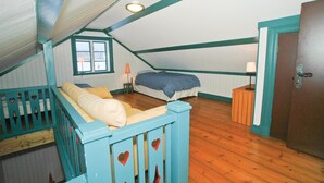 Een knus slaapkamer op zolder met schuine wanden, een bed, een sofa en een kleine tafel.