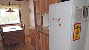 Eine kleine Küche mit Holzausstattung, einem weißen Bosch-Kühlschrank und einem Esstisch mit Stühlen.
