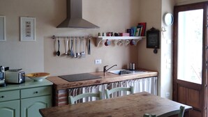 A kitchen with a wooden table and chairs, a sink, and various utensils hanging on the wall.