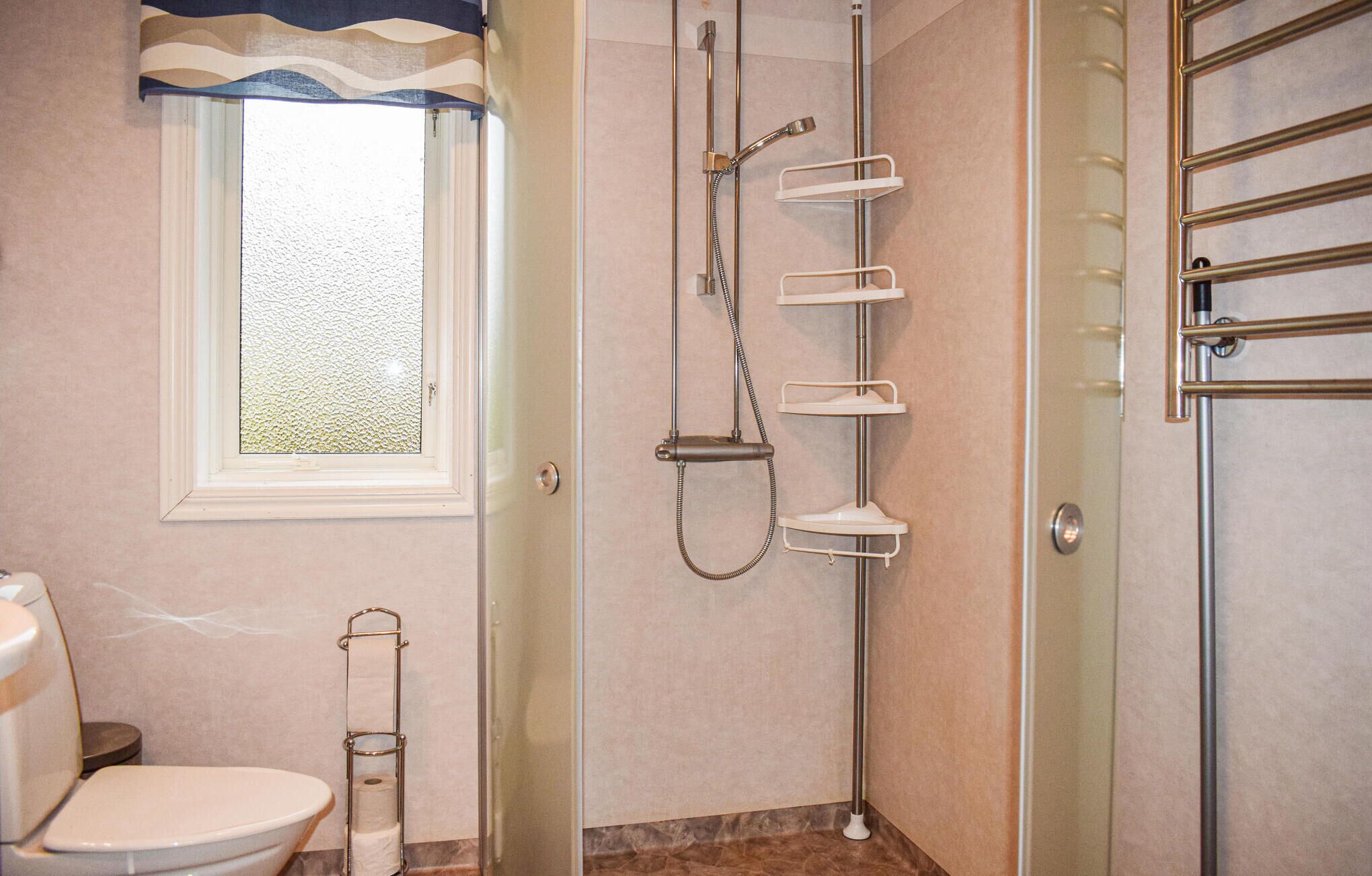 A bathroom with a toilet, a shower with a glass door, and a towel rack.