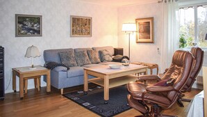 Ett vardagsrum med en soffa, ett soffbord, en fåtölj i läder och en lampa.