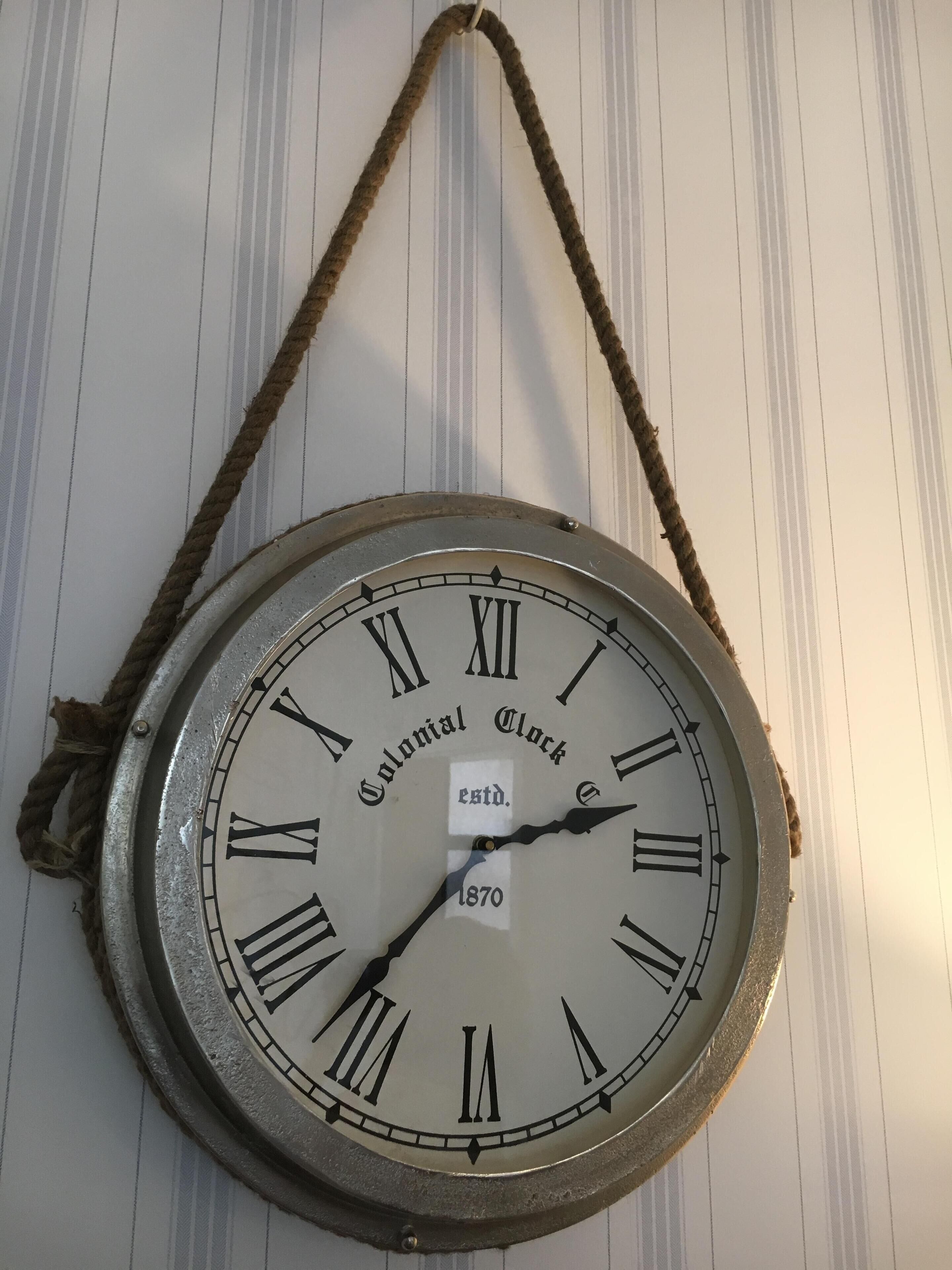 A wall-mounted clock with Roman numerals and the text "Colonial Clock" and "estd. 1870".