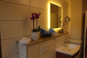 Une salle de bain avec un lavabo, un miroir et une orchidée en pot.
