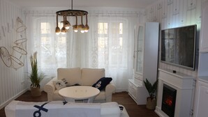 Ein Wohnzimmer mit Kamin, Fernseher und einer Couch mit Zierteksten.