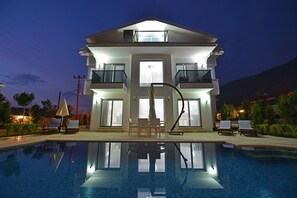 Un hôtel moderne à plusieurs étages, doté d’une piscine, d’un espace extérieur aménagé et de balcons.