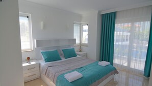 A bedroom with a large bed, a nightstand, a dresser, and a window with curtains. - 3 bedroom luxury villa in ovacik oludeniz for rent (fethiye)