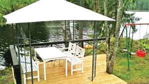 A wooden deck with a white table and chairs, a swing set, and a canopy. - Lovely home in Tived with WiFi (Tived)