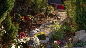 A garden with a stone pathway, various plants, and a bench. - Holiday house Fichtelgebirgshaus (Hüttstadl)