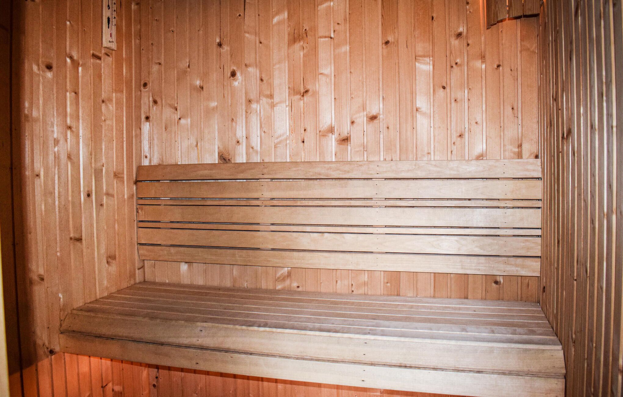 Een houten bankje in een kamer met verticale houten lambrisering.
