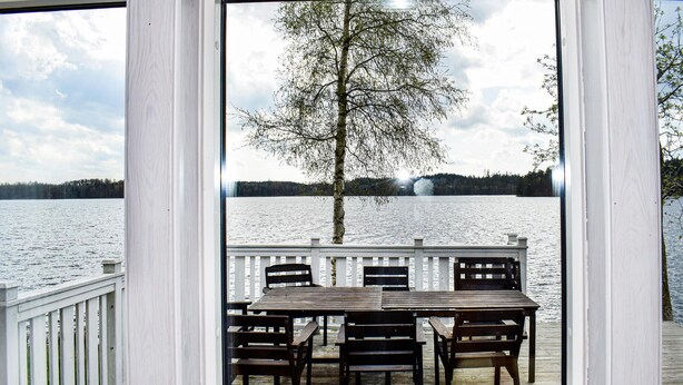 Une terrasse en bois avec une table et des chaises donnant sur un lac.