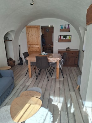A cozy dining area with a wooden table and chairs, a blue sofa, and a small round table.
