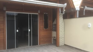 A building with a wooden exterior, a glass door, and a brick wall. - Bangalôs do Parque (Penha)
