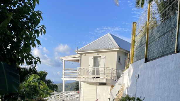 A pool area with a stone pathway, seating, and a view of a house with a balcony.