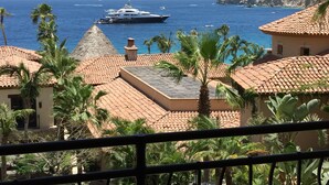 A coastal view with a yacht in the distance, palm trees, and buildings with red-tiled roofs. - The Hacienda Beach Club & Residence 3 bedrm./4 bathroom. (Cabo San Lucas)