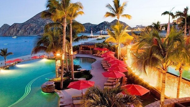 A resort pool area with palm trees, lounge chairs, and umbrellas. - The Hacienda Beach Club & Residence 3 bedrm./4 bathroom. (Cabo San Lucas)