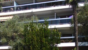 Ein mehrstöckiges Gebäude mit Balkonen, einer Palme und einem Schild mit der Aufschrift "CORINTH".
