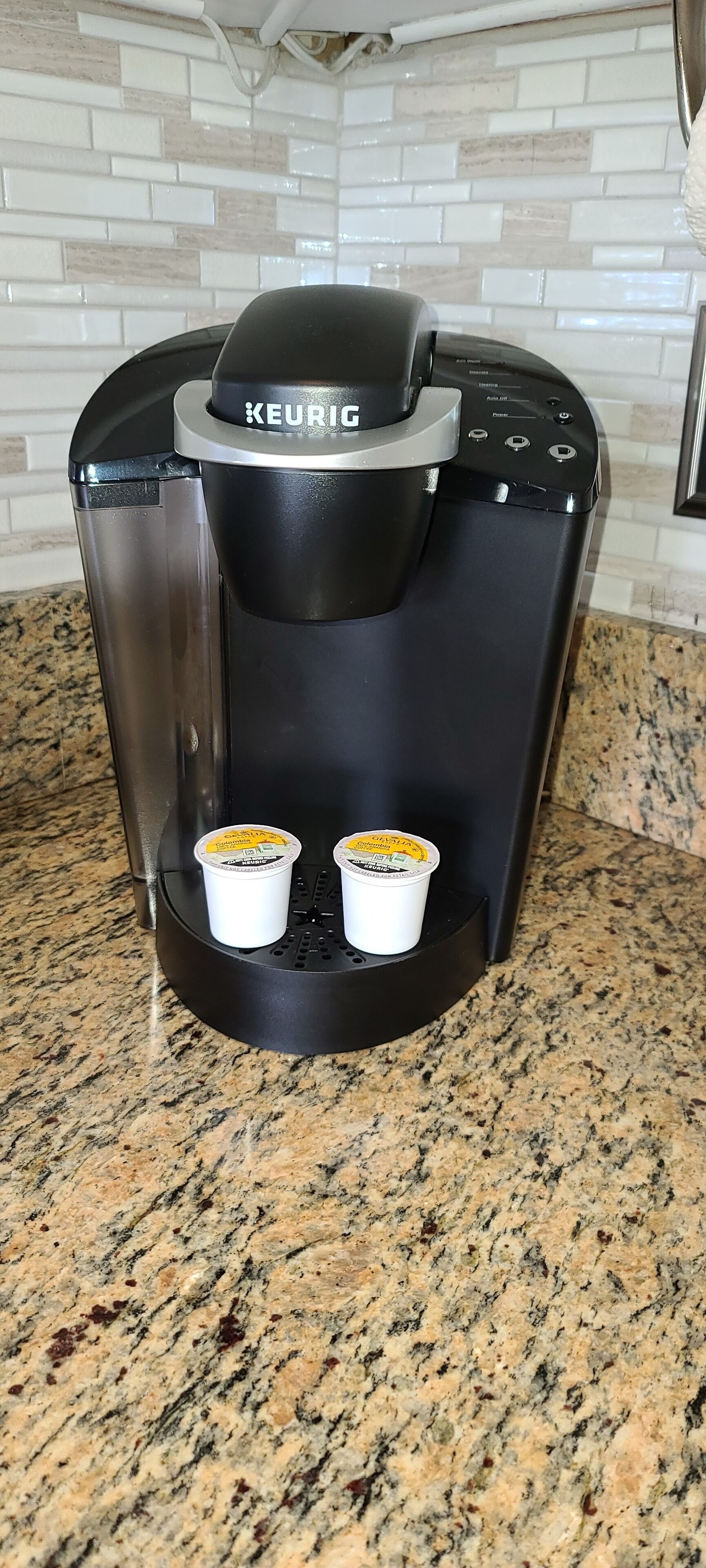 Una cafetera Keurig con dos vasos de café desechables sobre una encimera de granito.
