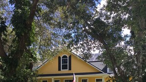 A yellow house with a porch and an American flag.