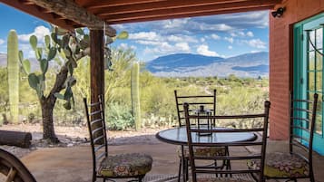 A patio with a table and chairs, a cactus, and a view of mountains.