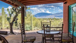 Un patio con una mesa y sillas, un cactus y vistas a las montañas.