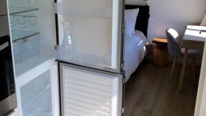 A compact room with a bed, a desk, and a refrigerator. - Maisonnette de Senlis rated 3*. Calm and excellent comfort (Senlis)