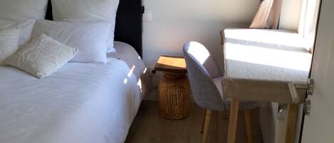 A bedroom with a bed, bedside table, chair, lamp, and a small round table.