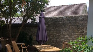 An outdoor patio with wooden furniture, including a table and chairs, and a purple umbrella. - Maisonnette de Senlis rated 3*. Calm and excellent comfort (Senlis)