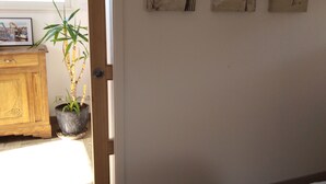 Una habitació amb un llit, un taulell de fusta, una planta en test i tres quadres penjats a la paret.