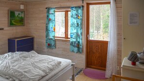 A bedroom with a bed, a dresser, a window with curtains, and a door leading outside.