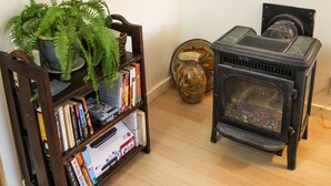 A cozy room with a wooden bookshelf, a vintage stove, and framed pictures on the wall. - Sam Hill's Cottage In historic Prescott Arizona (Prescott)
