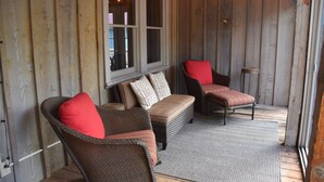 A wooden porch with wicker chairs and a bench, string lights, and a window with blinds. - Cozy & Chic Rustic Retreat-Luxury Log Home Near Downtown, Opry and Much More (Nashville)