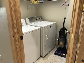 A laundry room with two stacked washers and dryers, a vacuum cleaner, and a wooden door. - 1 Mile to ski Area / Amazing Views / Hot Tub - Five Star Reviews (Granby)