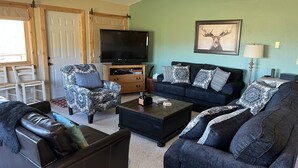 A living room with a sofa, two armchairs, a coffee table, a TV, and a framed picture on the wall. - 1 Mile to ski Area / Amazing Views / Hot Tub - Five Star Reviews (Granby)