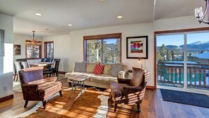 Amplia sala de estar con un gran ventanal, comedor y vistas a las montañas.